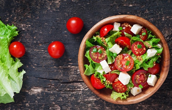 Colourful bowl with greens, tomatoes, grains and seeds